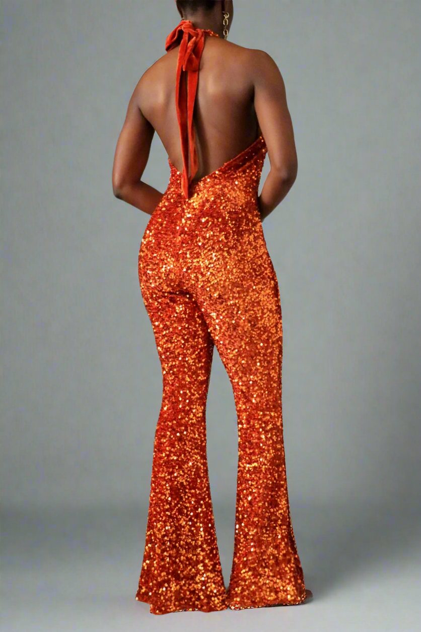 The model is wearing the front view of a brunt orange sequin halter backless flare leg jumpsuit
