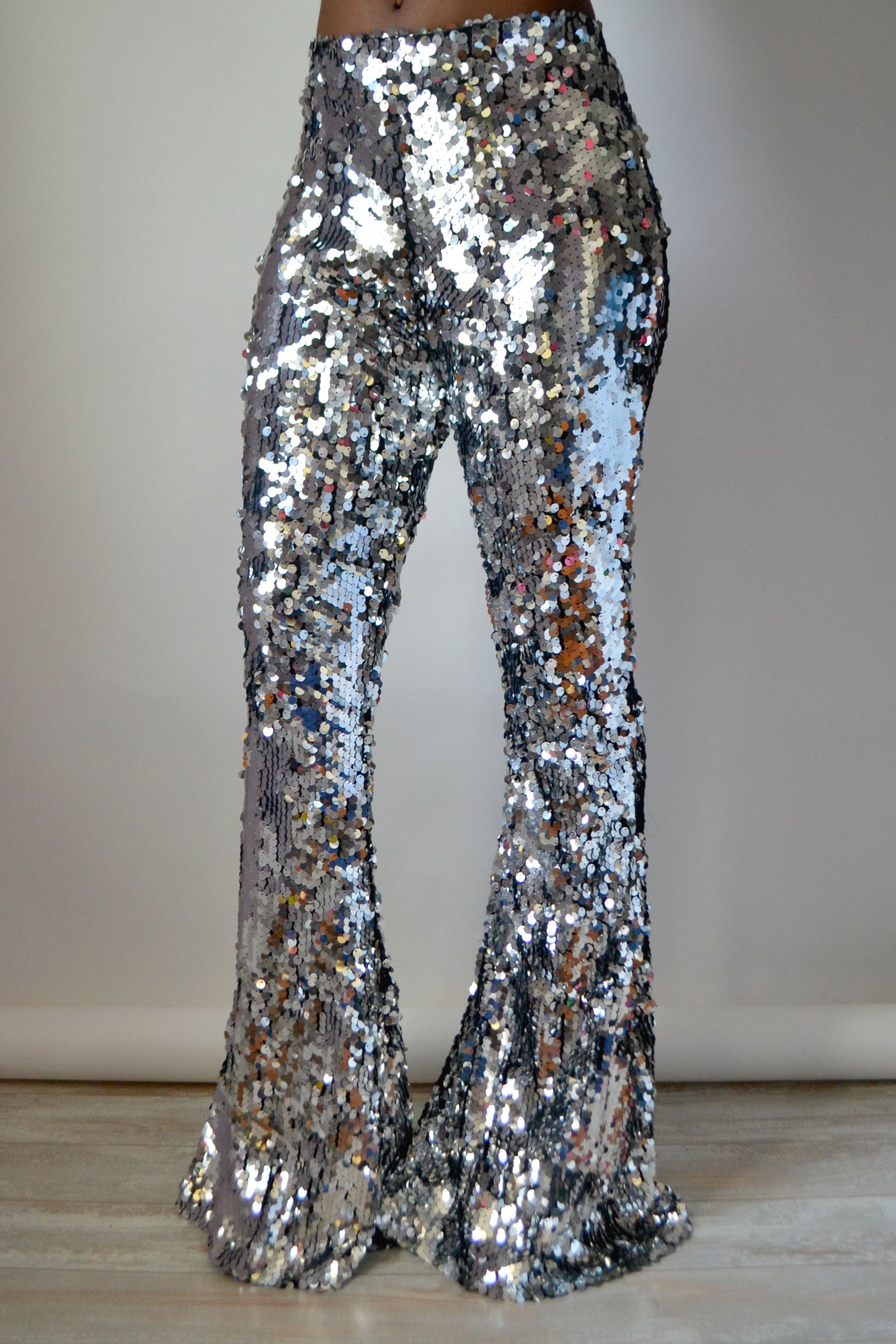 Silver sequin bell-bottom pants on a plain background