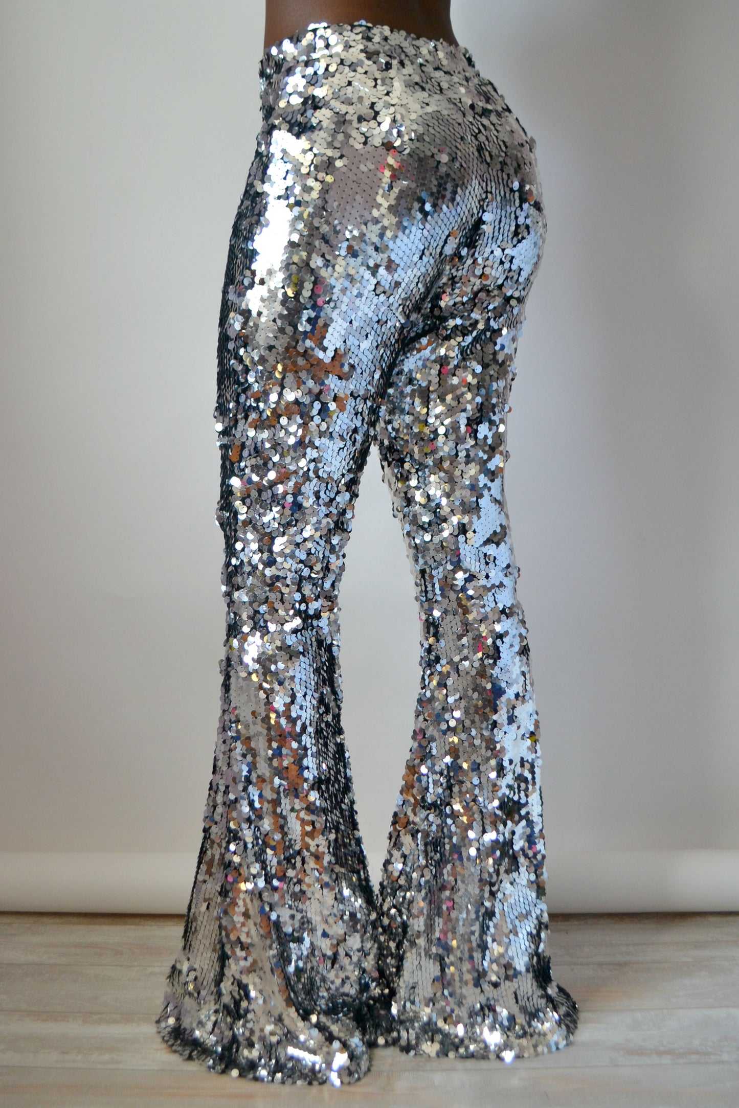 Back view of silver sequin pants on a plain background