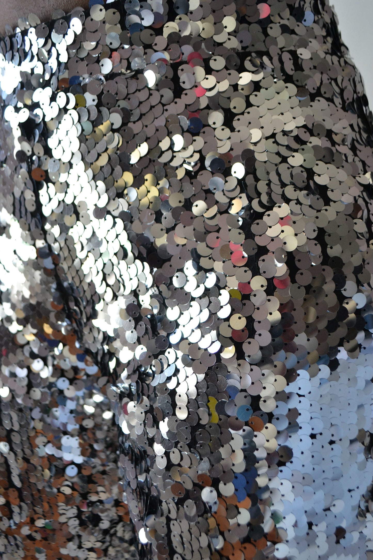 Close-up of a sequined fabric with multicolored sequins on a textured background