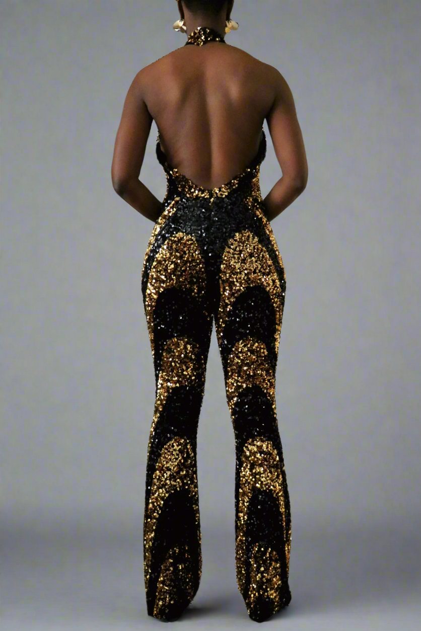 Back view of a model wearing a black & gold sequin swirl pattern halter jumpsuit. Backless halter is a deep V-neckline drops to zipper opening at waistline