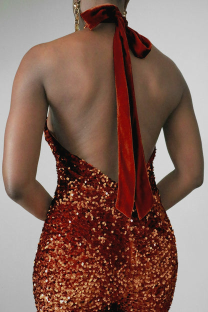 Back close-up of a model wearing a brown sequin halter jumpsuit on a plain background