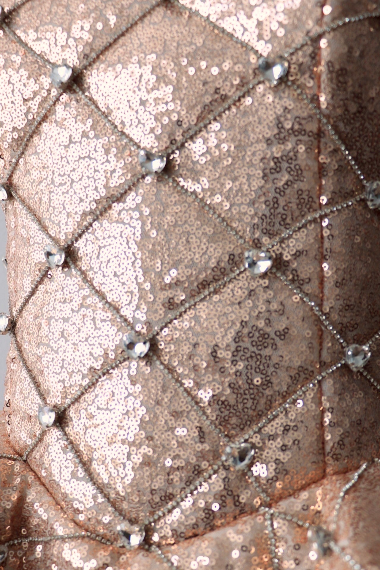 Close-up of a rose gold quilted  sequin corset with diamond quilt pattern with rhinestone heart embellishments.