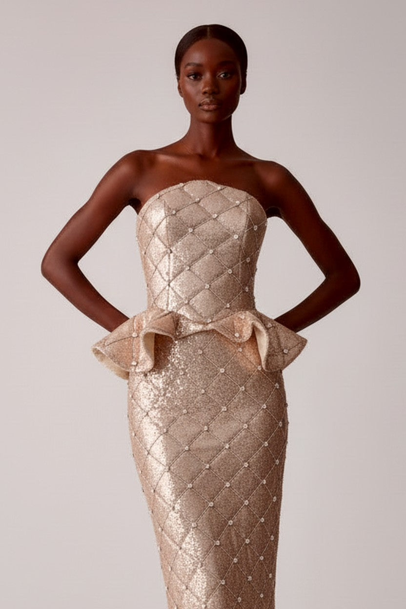 Woman wearing a strapless, quilted evening gown with a bow detail on a plain background