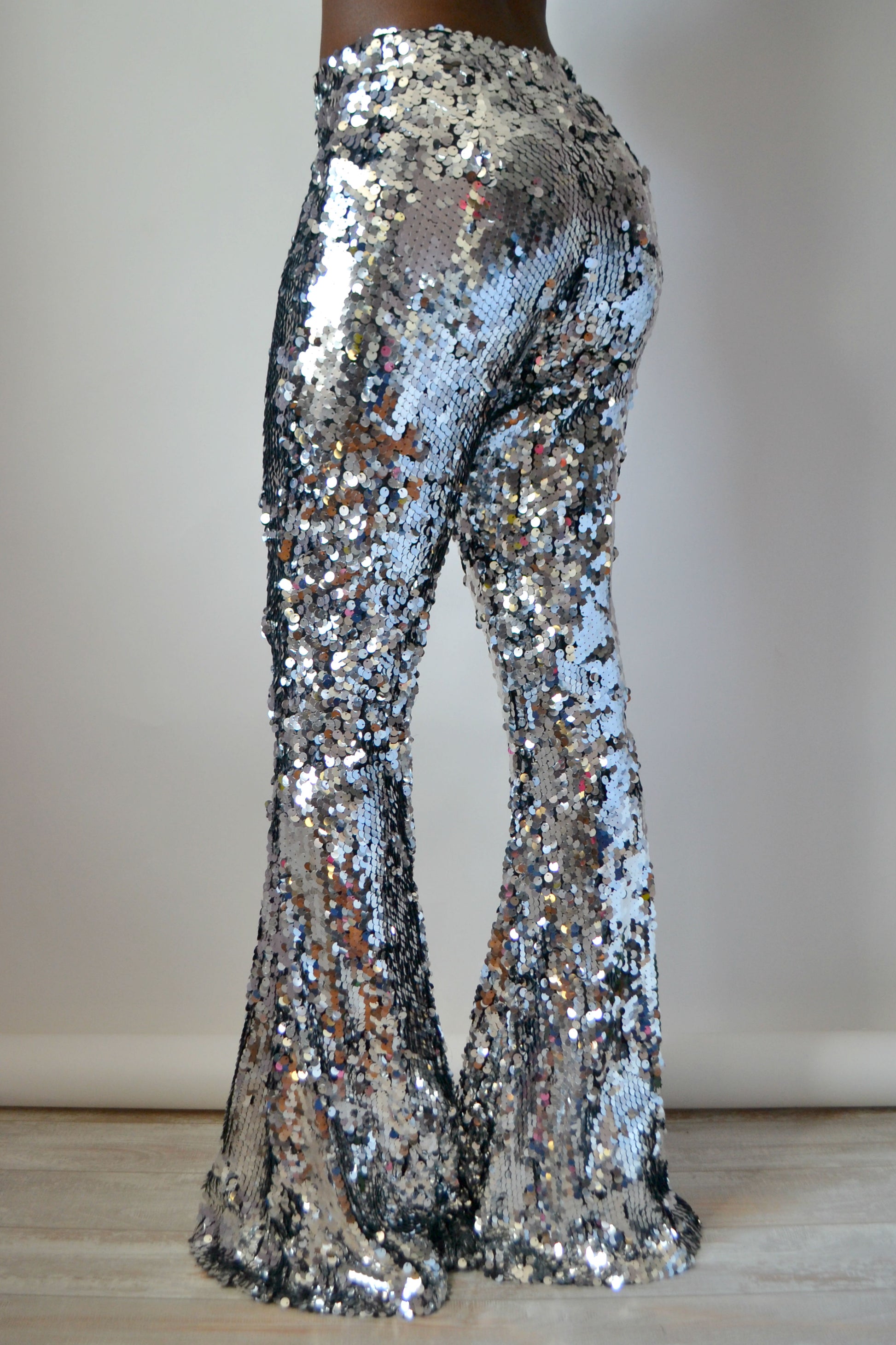 Back view of silver sequin pants on a plain background