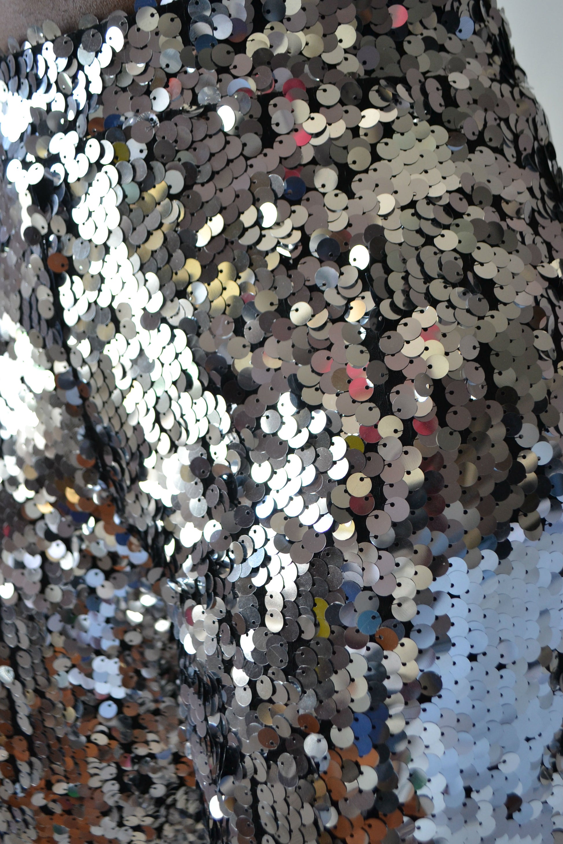 Close-up of a sequined fabric with multicolored sequins on a textured background