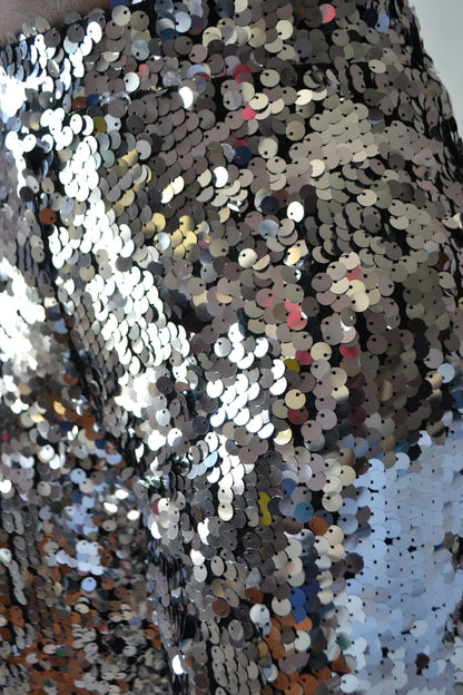 Close-up of a sequined fabric with multicolored sequins on a textured background