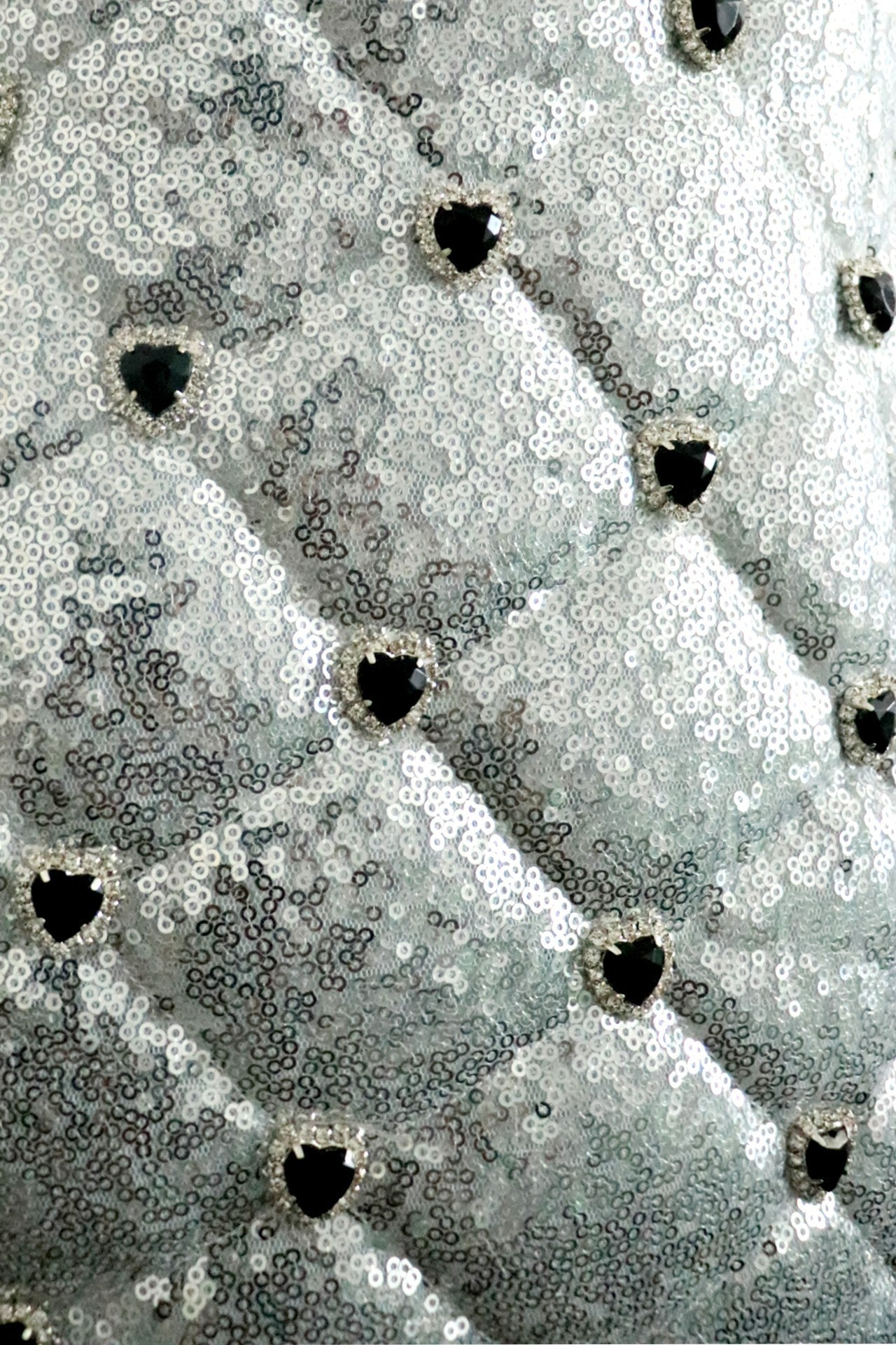 close up detail of sequin quilt pattern with black heart rhinestone detail on pattern