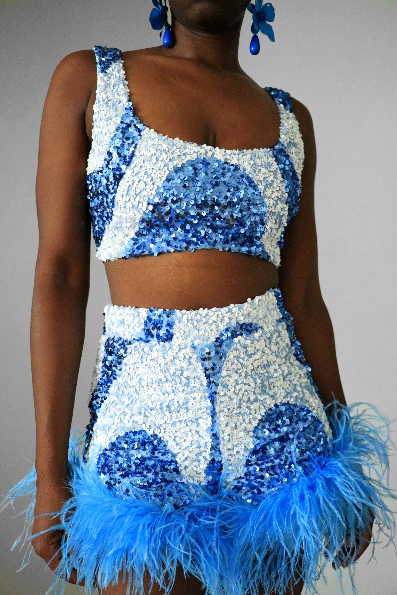 Full view of model wearing blue & white sequin swirl square neck crop                with match blue & white sequin swirl feather high waist shorts