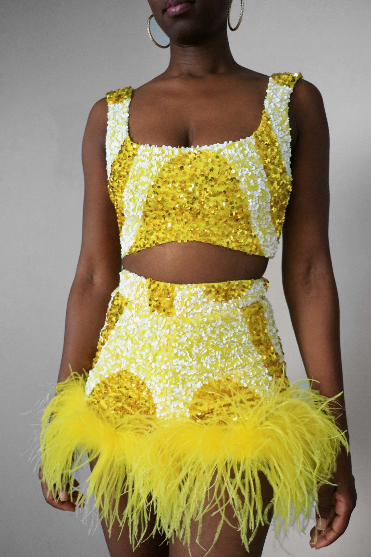 Full front view of a model wearing a yellow and white sequin swirl square neck crop top  with matching sequin feather shorts