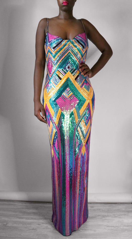 Woman wearing a colorful geometric-patterned sequin dress against a plain background
