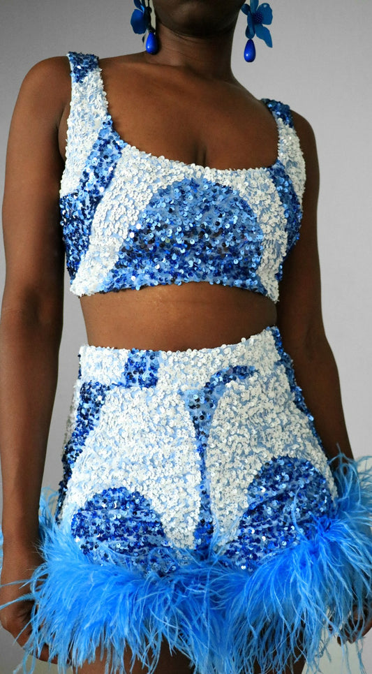 Full view of model wearing blue & white sequin swirl square neck crop                with match blue & white sequin swirl feather high waist shorts