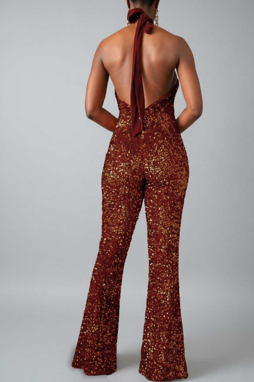 Back view of a model wearing a brown sequin halter jumpsuit with a plain background