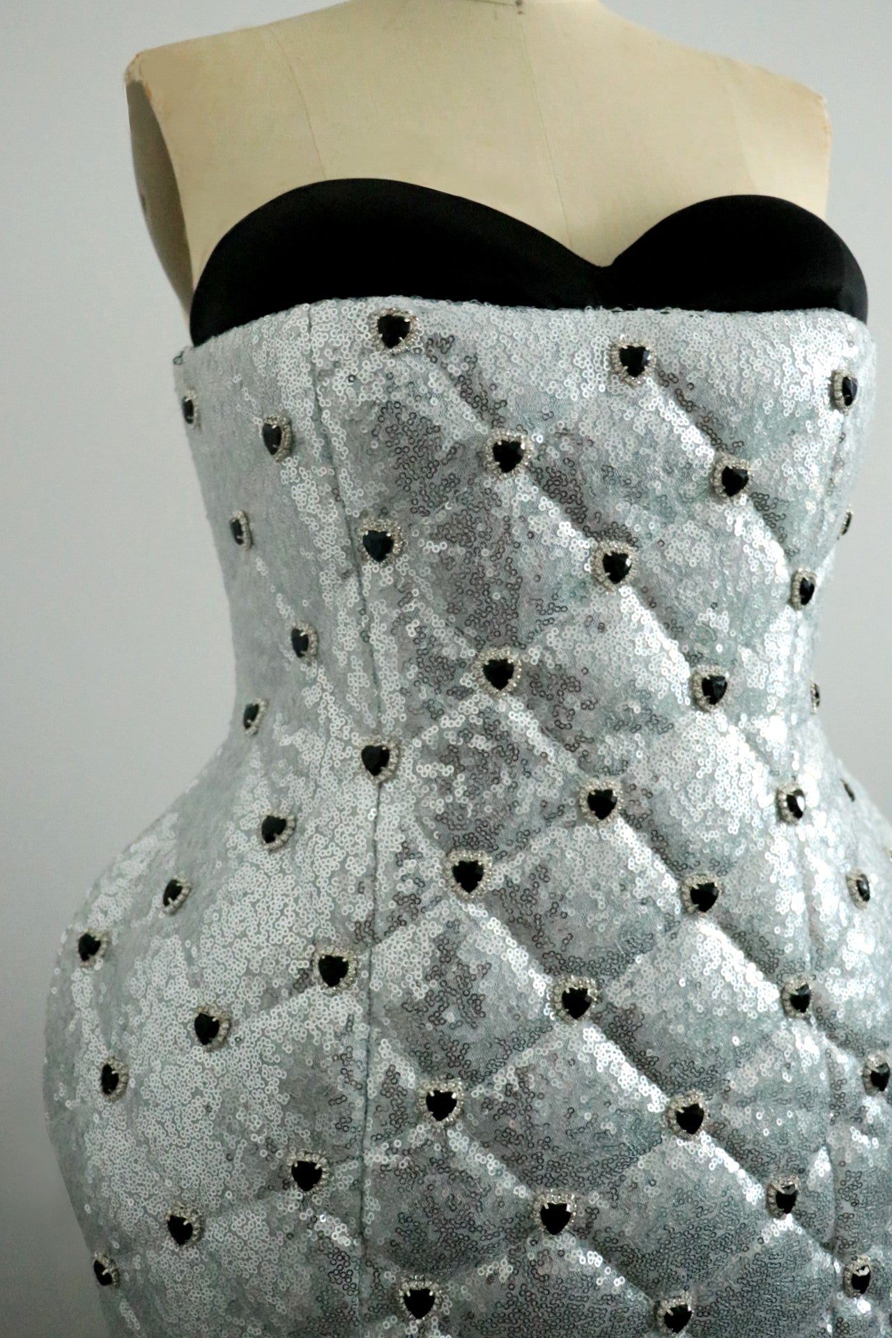 Black strapless top with a textured silver sequin dress on a mannequin against a gray background