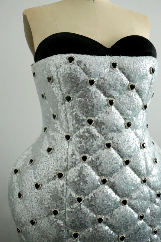 Black strapless top with a textured silver sequin dress on a mannequin against a gray background