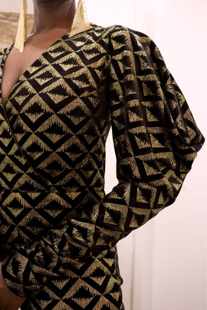 Black and gold geometric-patterned jumpsuit with long sleeves on a plain background