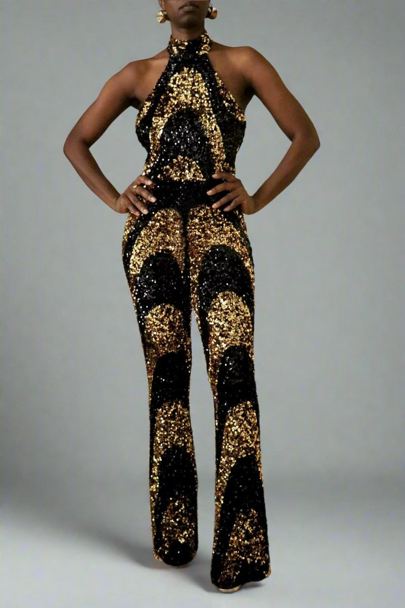 Front view of model wearing a black & gold sequin swirl pattern halter jumpsuit 